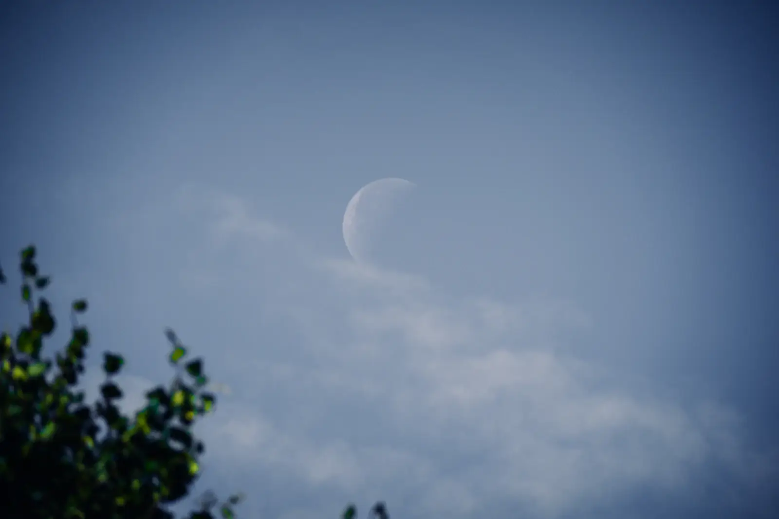 Une demi-lune à travers les nuages, dans un ciel bleu