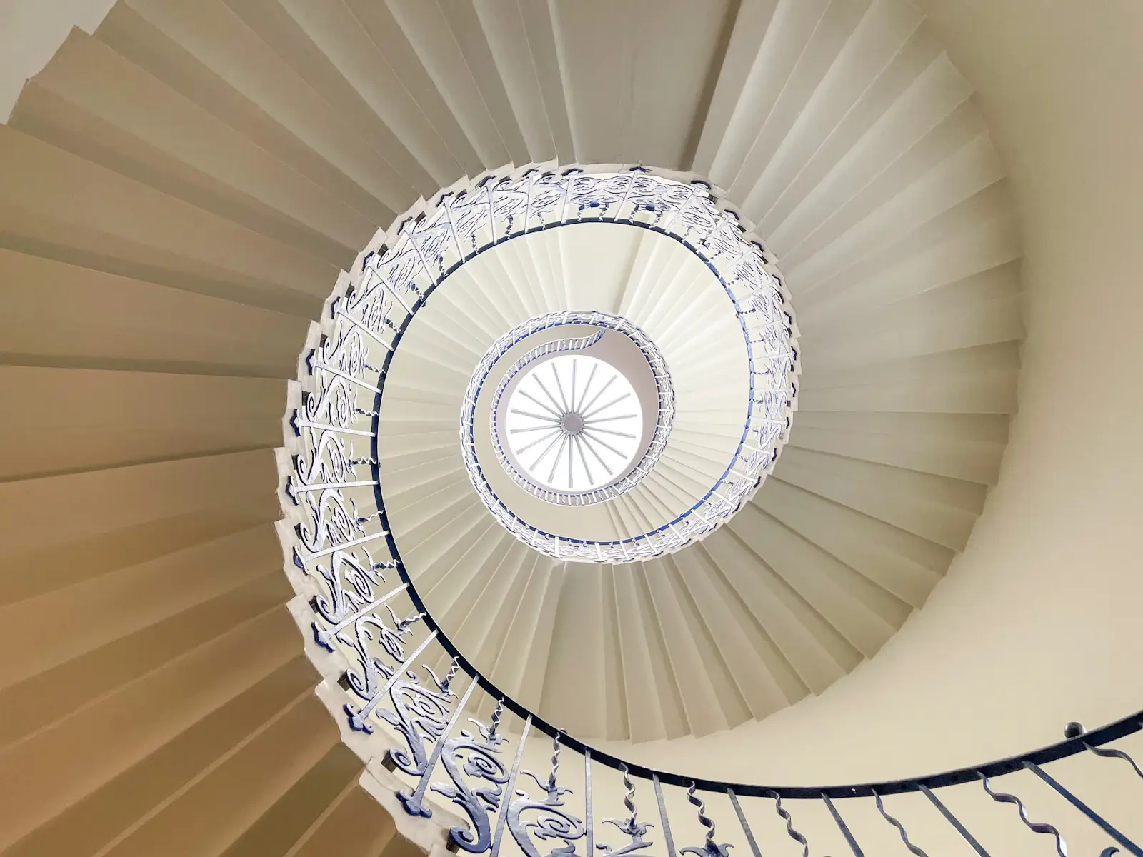 Un escalier en colimaçon clair vu d’en bas, sous un puits de lumière